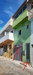 un bâtiment vert avec une hache devant dans l'établissement Kitnet montanha mágica, à São Thomé das Letras