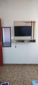 un téléviseur à écran plat fixé au mur avec un miroir dans l'établissement Kitnet montanha mágica, à São Thomé das Letras