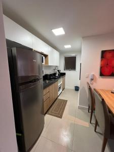 a kitchen with a stainless steel refrigerator and a table at Flat no centro de Torres in Torres