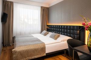 布拉格艾达酒店的一间卧室配有一张带皮革床头板的大床