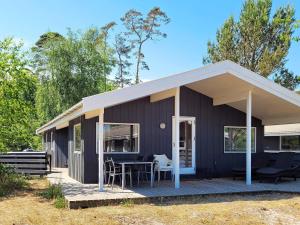 a black house with a deck with a table at 8 person holiday home in Nexø-By Traum in Snogebæk