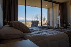 a large bed in a room with a large window at NOI Lodge Entre Viñedos in La Consulta