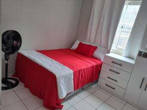 een slaapkamer met een bed met een rode deken en een raam bij Apartamento no centro de Ananindeua in Ananindeua
