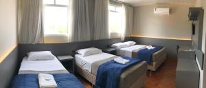 a hospital room with three beds and windows at Nap Hotel in Ponta Grossa