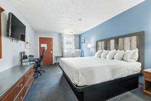 a hotel room with a large bed and a desk at Days Inn & Suites by Wyndham Terre Haute in Terre Haute
