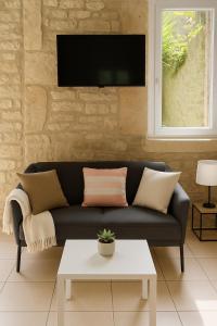 a living room with a couch and a tv on a wall at Le Nid d Abbaye in Caen