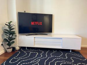 a tv sitting on top of a white entertainment center at Cosy Ground Floor Walk to Adelaide Oval, City, Zoo & More in Adelaide