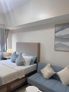 a bedroom with a bed and a blue couch at ARA Condotel in Cebu City