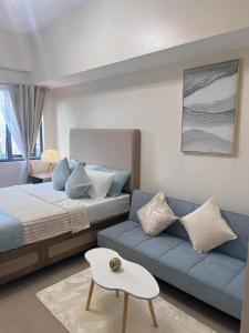 a bedroom with a bed and a blue couch at ARA Condotel in Cebu City