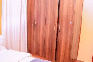 a wooden cabinet next to a bed in a bedroom at Berry's Furnished Apartment in Ruaka