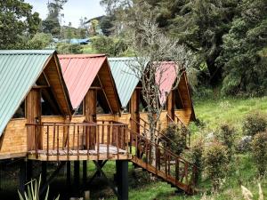 a log cabin with a deck and red roof at Cabañas del bosque - La casa en la piedra in Choachí