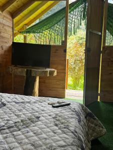 Un dormitorio con una cama y un televisor de pantalla plana. en Cabañas del bosque, en Choachí