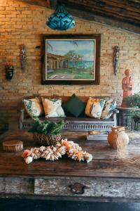 a room with a bench with pillows and a painting at Casarão Alto Mucugê in Arraial d'Ajuda