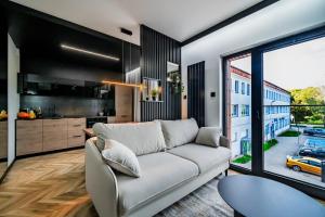 a living room with a couch and a kitchen at Apartament Parkya Slow by Warmia4Rent in Olsztyn