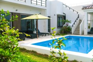 a swimming pool with an umbrella next to a house at Blue Ocean Resort - Vacation STAY 03044v in Ishigaki Island