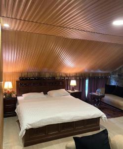 a bedroom with a large bed with a wooden ceiling at Haven Hilltop Cottage, Dunga Gali in Dunga Gali +19 photos