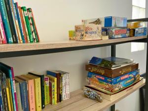 a bunch of books sitting on a shelf at Maison Bleu-Oxygène Accès direct au bassin Manapany-Les-Bains in Saint-Joseph