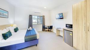 a hotel room with a bed and a desk and a tv at Club Maclean Motel in Maclean