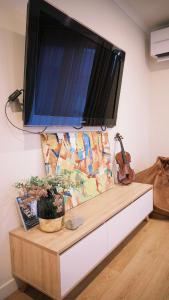 a flat screen tv on a wall above a table with a guitar at Maunga Hukarere in Lake Tekapo +7 photos