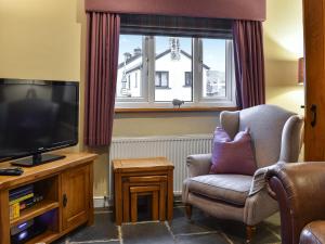 ein Wohnzimmer mit Sessel und Fernseher in der Unterkunft Penny Rigg Cottage in Coniston