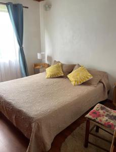 a bedroom with a bed with two yellow pillows at Cabañas Rapanui keka in Hanga Roa