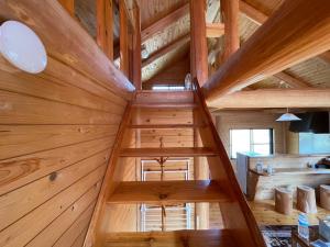 an attic room with wooden walls and wooden stairs at Karin in Minami Aso