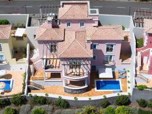 an aerial view of a pink house with a swimming pool at Balancal Apartments and Villas Palheiro Village in Funchal