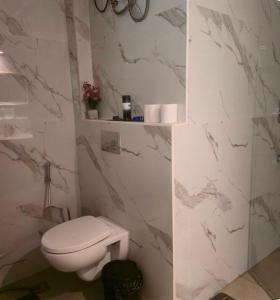 バンガロールにあるSuite 001の白いトイレと大理石の壁が備わるバスルーム