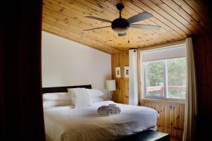 a bedroom with a large bed with a ceiling fan at Serendipity 5 BR Waterfront 4 Seasons, Hot Tub, Firepit, Close to Ski HIll in Haliburton