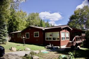 a red cabin in the middle of a forest at Serendipity 5 BR Waterfront 4 Seasons, Hot Tub, Firepit, Close to Ski HIll in Haliburton