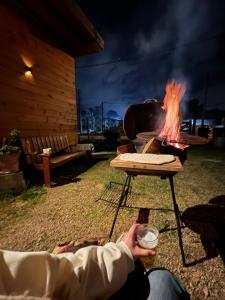 a person holding a drink and a fire pit at Beautiful romantic cabin for a relaxing getaway in Ciudad de la Costa