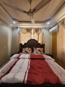 a bedroom with a large bed with a red and white comforter at The Nobles Luxurious 2 Bedroom Apartment in Kumasi