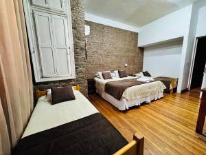 a bedroom with two beds and a brick wall at Hotel Casa Lyon in Santiago