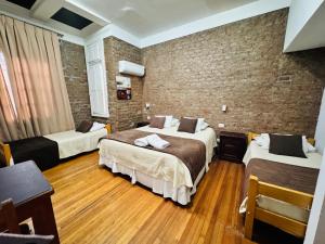 a hotel room with two beds and a brick wall at Hotel Casa Lyon in Santiago +21 photos