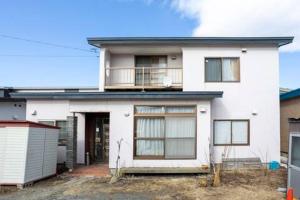 Una casa blanca con un balcón encima. en 80s stay 釧路, en Kushiro