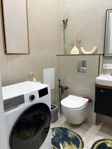 a bathroom with a washing machine and a toilet at Yassaui Apartments in Astana