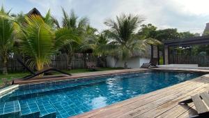 a swimming pool with a wooden deck and palm trees at Coco Beach in El Paredón Buena Vista