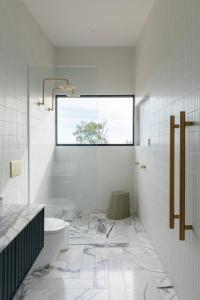 a white bathroom with a toilet and a window at Wherewithal Luxury Suites in Carlton