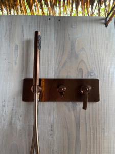 a shower with a hose attached to a wooden wall at Raiatea Treelodge in Taoru