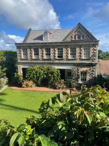 a large stone house with a yard at Lovely 1-bedroom wooden cabin in garden in Saint Paulʼs