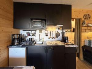 - une cuisine avec des placards noirs et un évier dans l'établissement Studio rénové avec balcon et parking aux Orres - FR-1-322-687, à Le Mélézet 3 autres photos