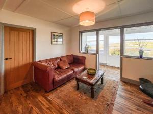 a living room with a leather couch and a table at Bellair in Marhamchurch +23 photos