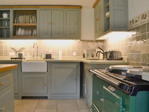 a kitchen with blue cabinets and a stove top oven at Glenmeanich Cottage - Uk33789 in Bridgend