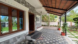 eine Veranda eines Hauses mit einer Bank und Fenstern in der Unterkunft Villa19, ECR in Tirupporūr + 9 Fotos