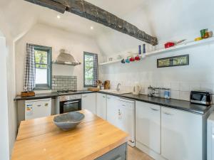 a kitchen with white cabinets and a wooden counter top at Bohemia Cottage in Royal Tunbridge Wells