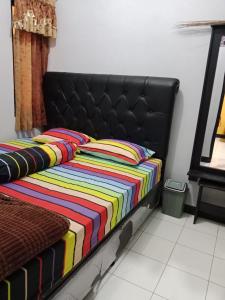 a bed with a colorful blanket on it in a room at Ananda Homestay Madasari in Madasari