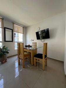Un comedor con mesa y sillas y un televisor. en Amanecer llanero, en Villavicencio