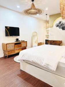 ein Schlafzimmer mit einem großen weißen Bett und einem Fernseher in der Unterkunft Sakha Villa Jogja With Privatepool in Jetis