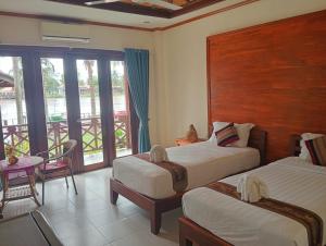 a hotel room with two beds and a balcony at Sengahloune Villa in Ban Khon +6 photos