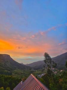 a sunset over a valley with mountains in the background at Tribano vattavada in Vattavada